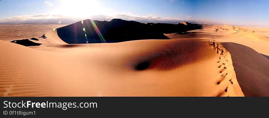 As far as they eye can see sand dunes in the desert with the sun low in sky casting deep shadows.