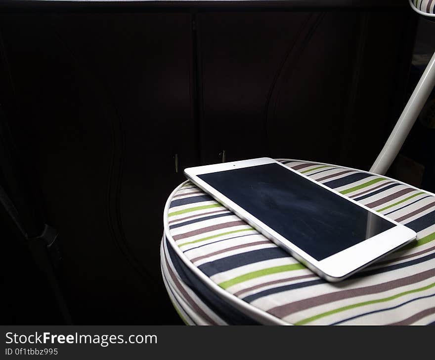 A close up of an Apple iPad on a striped chair. A close up of an Apple iPad on a striped chair.