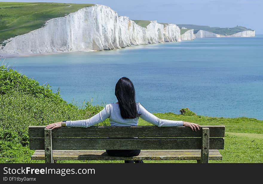 Woman Sitting on Deck Chair by Sea