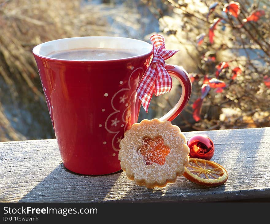 Cup of coffee on rustic window ledge with bow and Christmas biscuits, frosty garden in background. Cup of coffee on rustic window ledge with bow and Christmas biscuits, frosty garden in background.