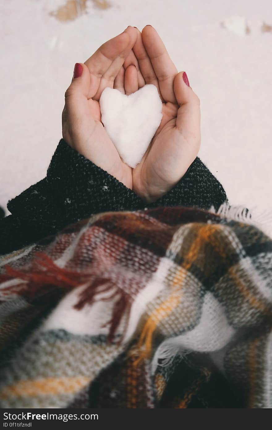 A woman holding a heart-shaped snow ball in her hands. A woman holding a heart-shaped snow ball in her hands.