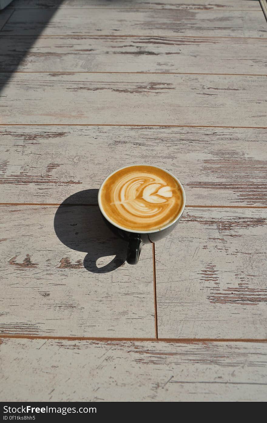 A cup of coffee with latte art on sunny day.