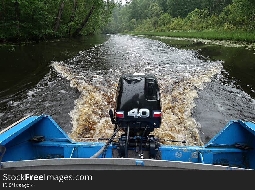 Outboard motor on back of boat in river. Outboard motor on back of boat in river.