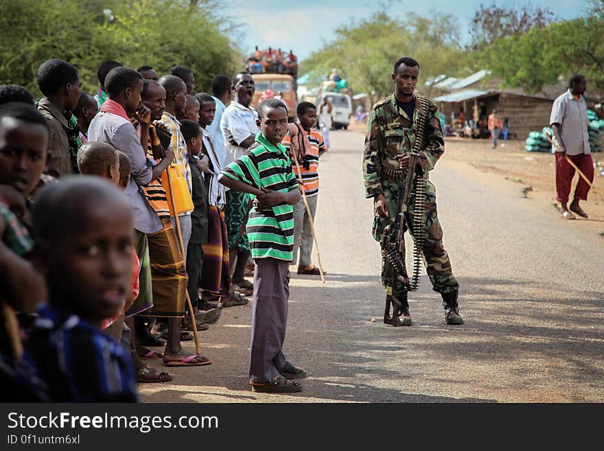 Residents of the village of Modmoday, look on as a soldier of the Somali National Army &#x28;SNA&#x29; keeps guard, approx. 40km east of the central Somali town of Baidoa. Burundian troops serving with the African Union Mission in Somalia &#x28;AMISOM&#x29; together with forces of the SNA have been mounting &#x27;snap&#x27; foot patrols in villages and areas to the east of Baidoa where Al Qaeda-affiliated extremist group Al Shabaab mount attacks against local herdsmen, villages and travelers along the busy Baidoa-Mogadishu road. The AMISOM troops also use the patrols as an opportunity to provide occasional free medical treatment and fresh, potable drinking water for residents in the area. AU/UN IST PHOTO / ABDI DAKAN. Residents of the village of Modmoday, look on as a soldier of the Somali National Army &#x28;SNA&#x29; keeps guard, approx. 40km east of the central Somali town of Baidoa. Burundian troops serving with the African Union Mission in Somalia &#x28;AMISOM&#x29; together with forces of the SNA have been mounting &#x27;snap&#x27; foot patrols in villages and areas to the east of Baidoa where Al Qaeda-affiliated extremist group Al Shabaab mount attacks against local herdsmen, villages and travelers along the busy Baidoa-Mogadishu road. The AMISOM troops also use the patrols as an opportunity to provide occasional free medical treatment and fresh, potable drinking water for residents in the area. AU/UN IST PHOTO / ABDI DAKAN.