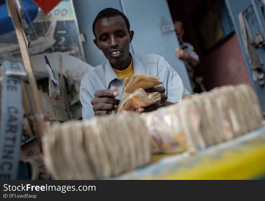 A money exchanger counts Somali shilling notes on the streets of the Somali capital Mogadishu. Millions of people in the Horn of Africa nation Somalia rely on money sent from their relatives and friends abroad in the form of remittances in order to survive, but it is feared that a decision by Barclays Bank to close the accounts of some of the biggest Somali money transfer firms – due to be announced this week - will have a devastating effect on the country and its people. According to the United Nations Development Programme &#x28;UNDP&#x29;, an estimated $1.6 billion US dollars is sent back annually by Somalis living in Europe and North America. Some money transfer companies in Somalia have been accused of being used by pirates to launder money received form ransoms as well as used by Al Qaeda-affiliated extremist group al Shabaab group to fund their terrorist activities and operations in Somalia and the wider East African region. AU/UN IST PHOTO / STUART PRICE. A money exchanger counts Somali shilling notes on the streets of the Somali capital Mogadishu. Millions of people in the Horn of Africa nation Somalia rely on money sent from their relatives and friends abroad in the form of remittances in order to survive, but it is feared that a decision by Barclays Bank to close the accounts of some of the biggest Somali money transfer firms – due to be announced this week - will have a devastating effect on the country and its people. According to the United Nations Development Programme &#x28;UNDP&#x29;, an estimated $1.6 billion US dollars is sent back annually by Somalis living in Europe and North America. Some money transfer companies in Somalia have been accused of being used by pirates to launder money received form ransoms as well as used by Al Qaeda-affiliated extremist group al Shabaab group to fund their terrorist activities and operations in Somalia and the wider East African region. AU/UN IST PHOTO / STUART PRICE.