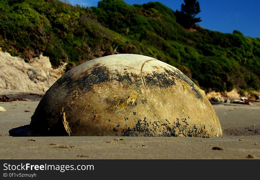 The Moeraki Boulders are unusually large and spherical boulders lying along a stretch of Koekohe Beach on the wave-cut Otago coast of New Zealand between Moeraki and Hampden. They occur scattered either as isolated or clusters of boulders within a stretch of beach where they have been protected in a scientific reserve. The erosion by wave action of mudstone, comprising local bedrock and landslides, frequently exposes embedded isolated boulders. These boulders are grey-colored septarian concretions, which have been exhumed from the mudstone enclosing them and concentrated on the beach by coastal erosion. The Moeraki Boulders are unusually large and spherical boulders lying along a stretch of Koekohe Beach on the wave-cut Otago coast of New Zealand between Moeraki and Hampden. They occur scattered either as isolated or clusters of boulders within a stretch of beach where they have been protected in a scientific reserve. The erosion by wave action of mudstone, comprising local bedrock and landslides, frequently exposes embedded isolated boulders. These boulders are grey-colored septarian concretions, which have been exhumed from the mudstone enclosing them and concentrated on the beach by coastal erosion