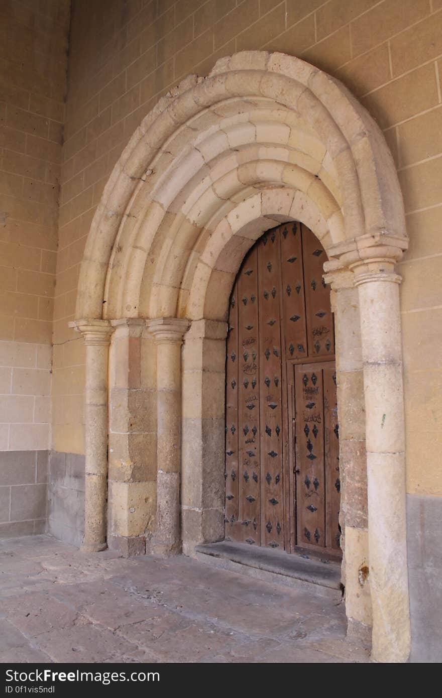 Wooden antique door under stone arches outside building. Wooden antique door under stone arches outside building.