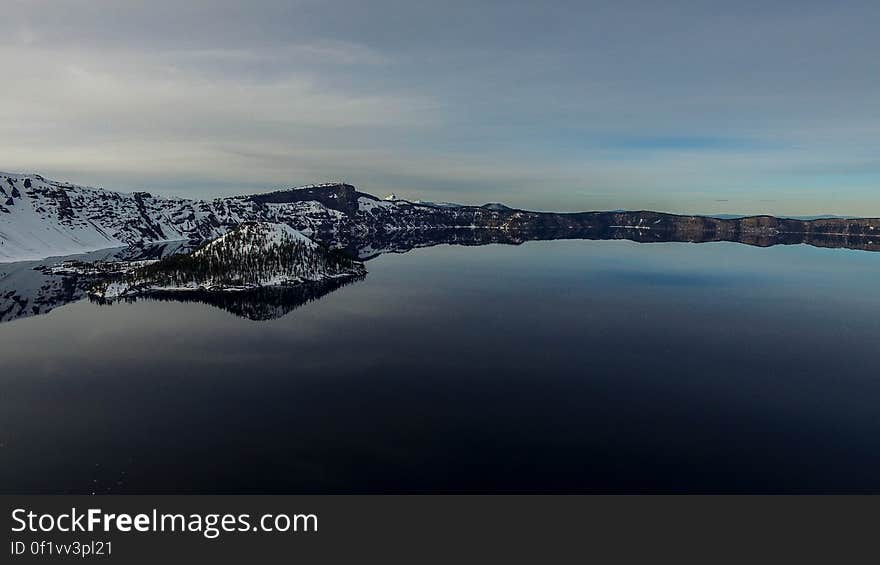 Snow covered landscape reflecting on calm lake. Snow covered landscape reflecting on calm lake.