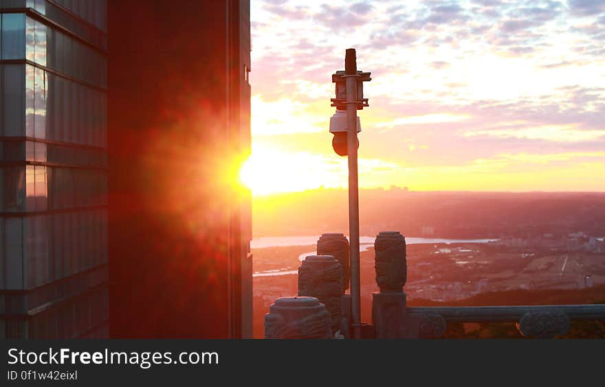 A view of city buildings with sun setting in the horizon. A view of city buildings with sun setting in the horizon.