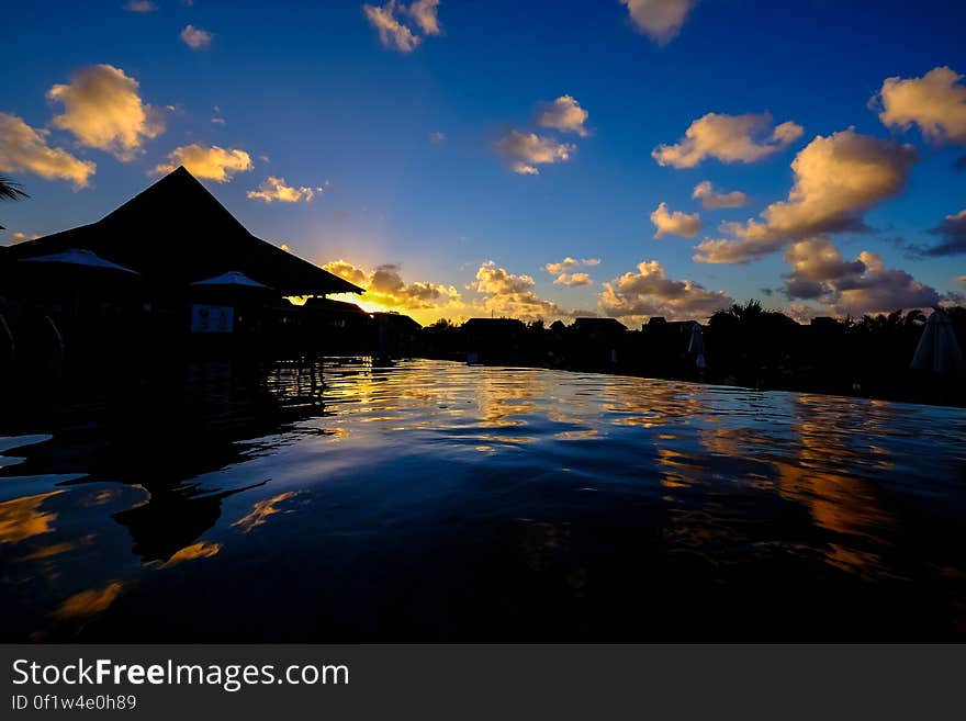 A view of houses near water with the sun setting in the background.