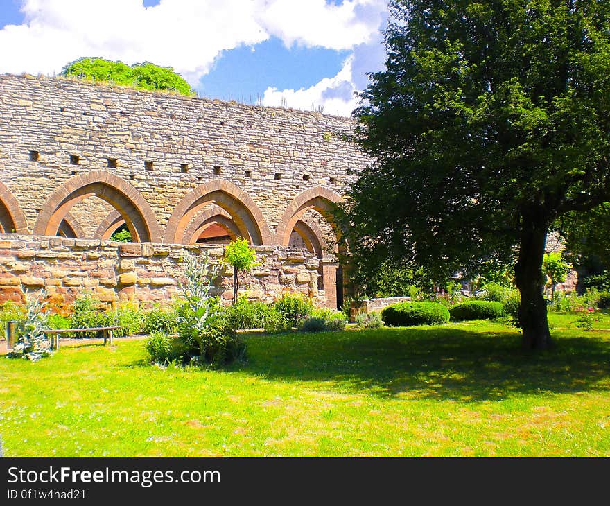 A view of a green garden with a part of an ancient wall. A view of a green garden with a part of an ancient wall.