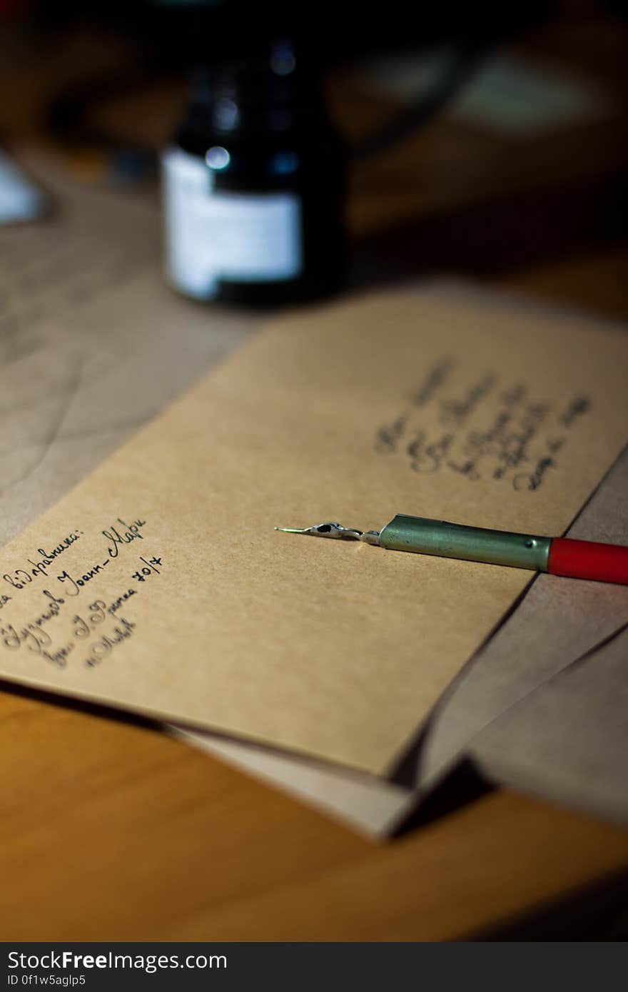 Old fashioned (retro) pen with steel nib and ink bottle lying next to a half finished letter or message on brown notepaper. Old fashioned (retro) pen with steel nib and ink bottle lying next to a half finished letter or message on brown notepaper.