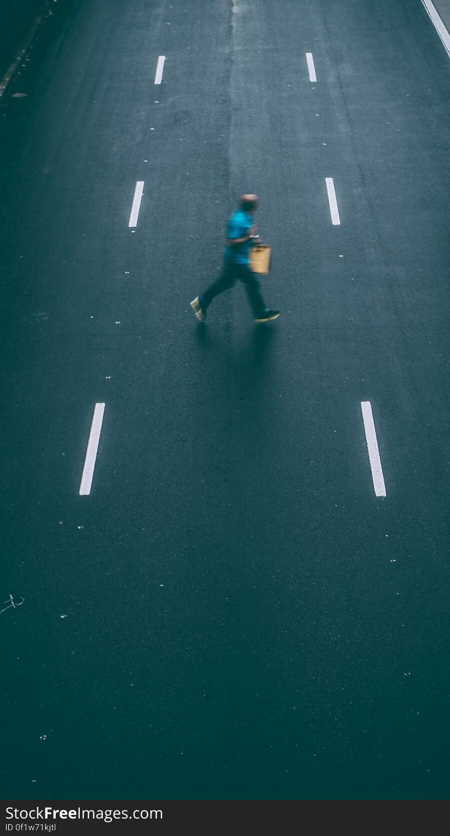 A man crossing an empty street. A man crossing an empty street.