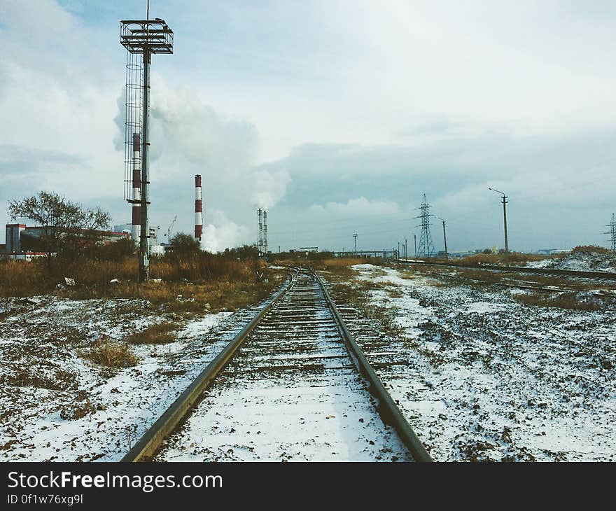 A railway covered with snow, heating plant and power lines in the background. A railway covered with snow, heating plant and power lines in the background.