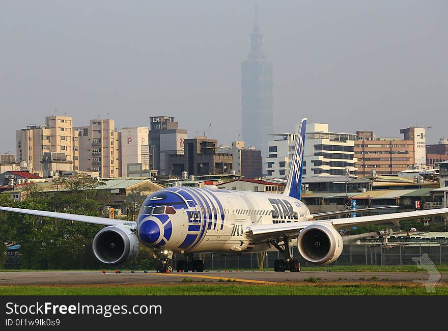 An airplane on a runway and buildings in the background. An airplane on a runway and buildings in the background.