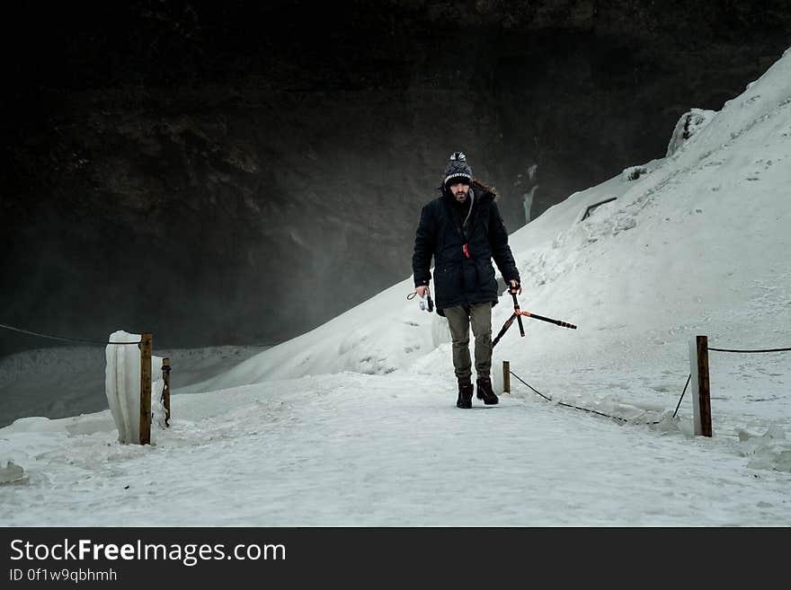 Man Wearing Black Jacket Brown Jeans and Black Shoes Walking on Snow