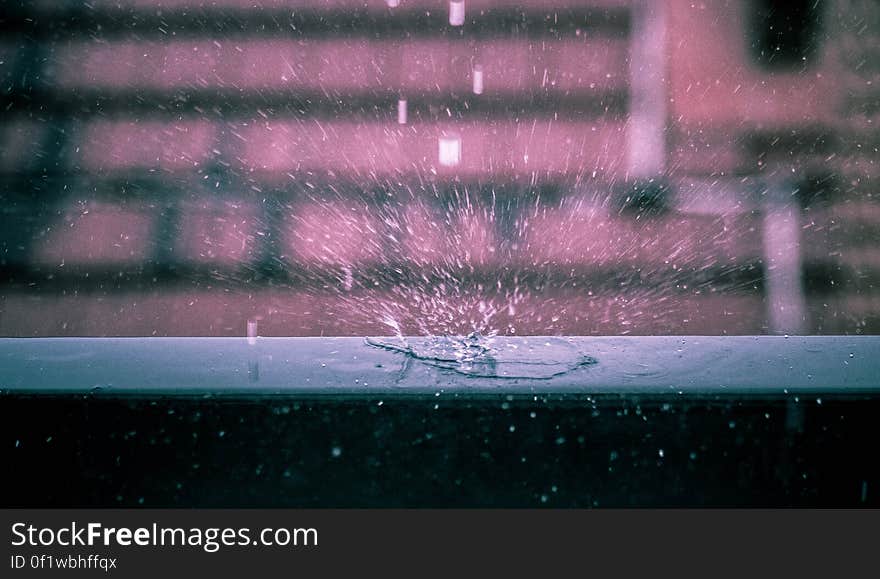 A close up of rain drops falling on a window seal. A close up of rain drops falling on a window seal.