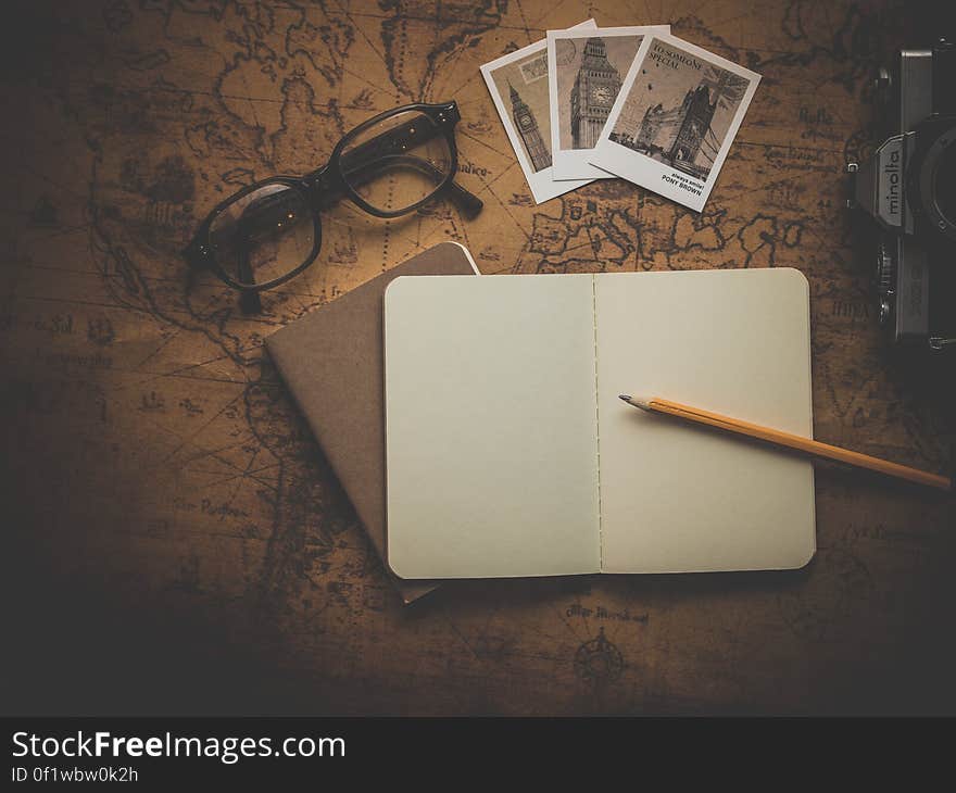 Black Framed Eyeglasses Beside Big Ben Pictures and Notebook