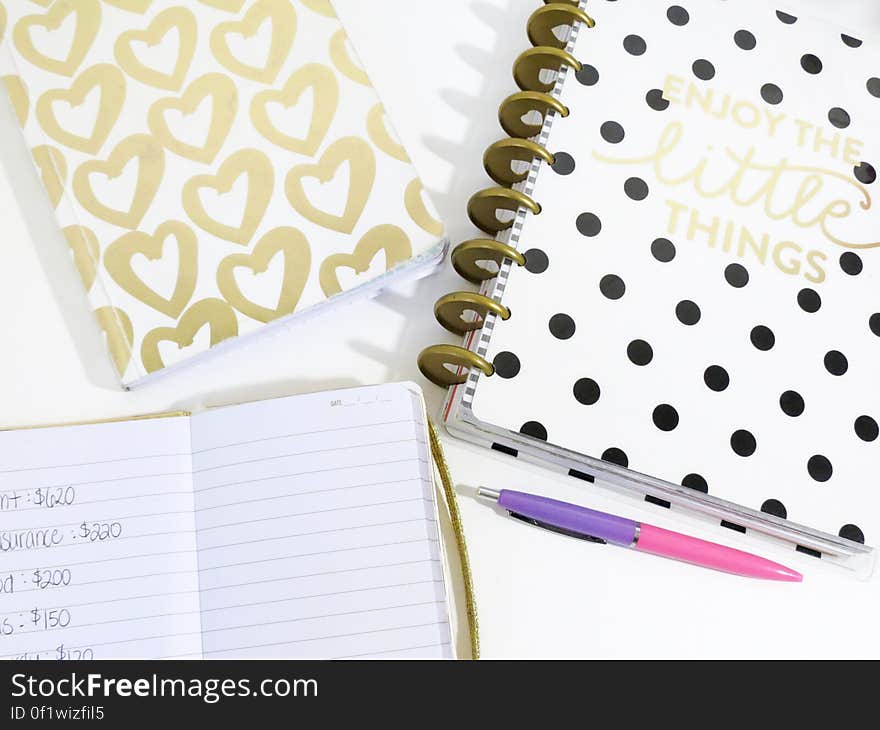 An opened notebook and a couple of journals on a table. An opened notebook and a couple of journals on a table.