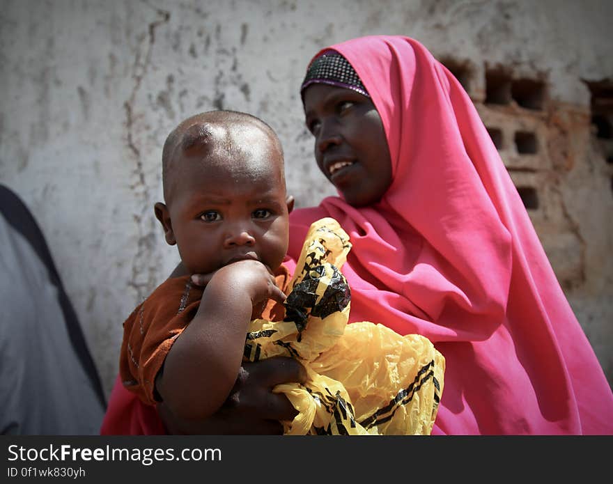 A women and her young child wait in the shade of a derelict building to see a doctor at a free medical clinic provided by the Kenyan Contingent serving with the African Union Mission in Somalia &#x28;AMISOM&#x29; in the southern Somali port city of Kismayo, 19 August 2013. Open 7 days a week and seeing an average of 80 patients a day from Kismayo and surrounding villages, AMISOM medical staff provide the free health care to Kismayo&#x27;s civilians, treating a variety of cases including malaria, respiratry tract infections, sexually transmitted infections and occassionally gunshot wounds. AU-UN IST PHOTO / RAMADAAN MOHAMED HASSAN. A women and her young child wait in the shade of a derelict building to see a doctor at a free medical clinic provided by the Kenyan Contingent serving with the African Union Mission in Somalia &#x28;AMISOM&#x29; in the southern Somali port city of Kismayo, 19 August 2013. Open 7 days a week and seeing an average of 80 patients a day from Kismayo and surrounding villages, AMISOM medical staff provide the free health care to Kismayo&#x27;s civilians, treating a variety of cases including malaria, respiratry tract infections, sexually transmitted infections and occassionally gunshot wounds. AU-UN IST PHOTO / RAMADAAN MOHAMED HASSAN.