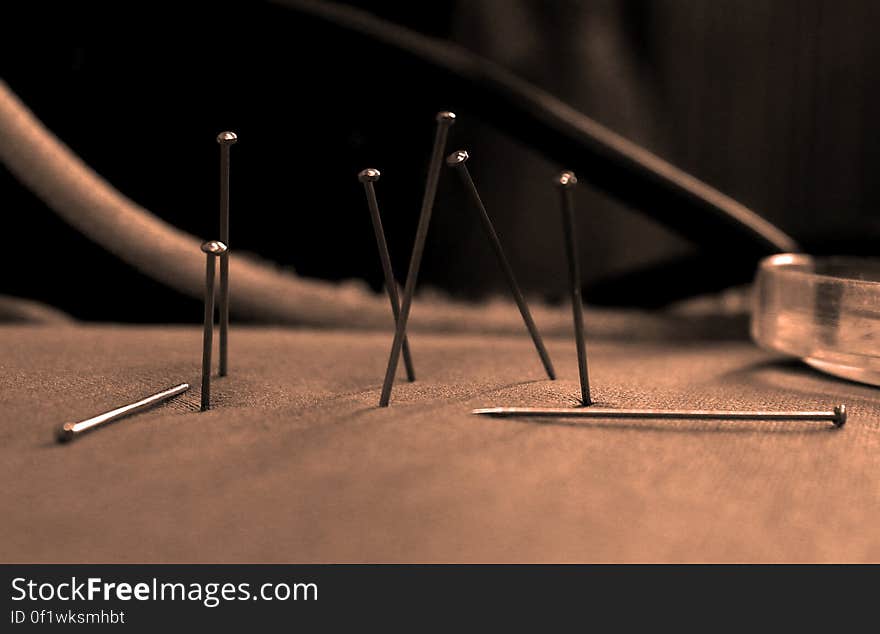 Macro view of group of small nails stuck in brown material surface. Macro view of group of small nails stuck in brown material surface.