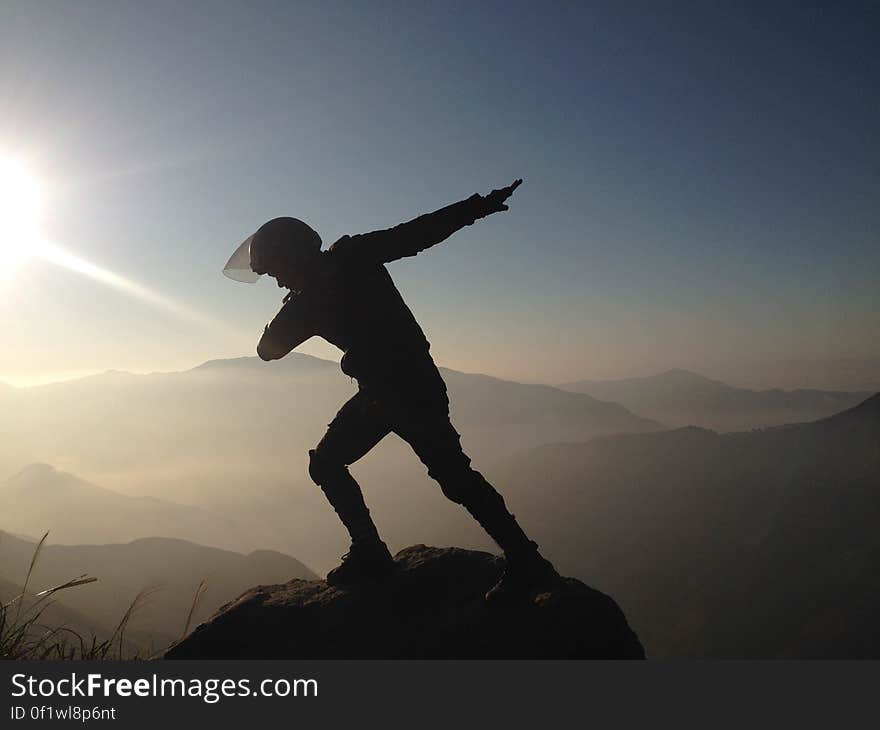 Mountaineer striking pose on boulder on top of mountain summit at sunset. Mountaineer striking pose on boulder on top of mountain summit at sunset.