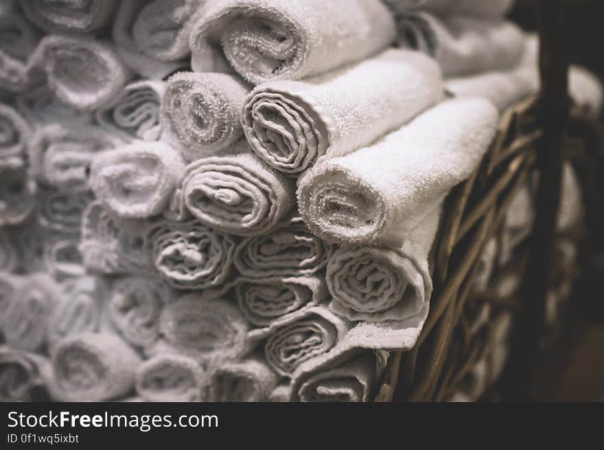 Stack of rolled white bathroom towels in basket.