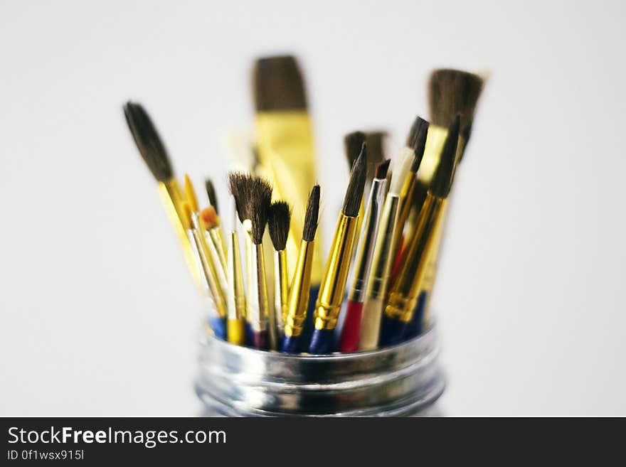 A close up of different paint brushes in a metal holder.