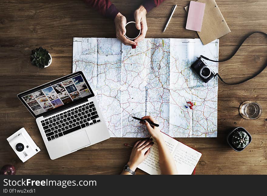 People reading a map on a table with laptop and camera, trip and vacation planning. People reading a map on a table with laptop and camera, trip and vacation planning.