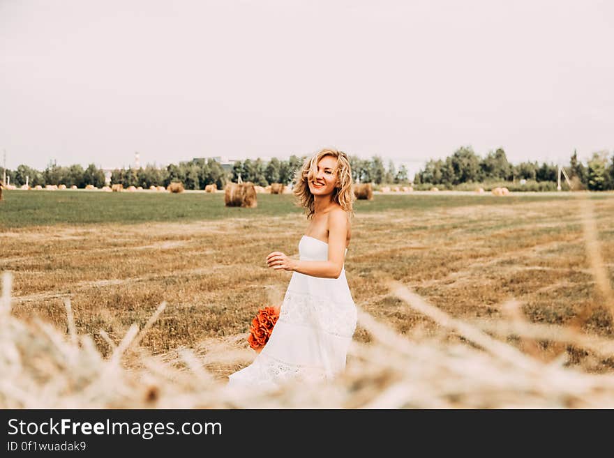 A woman wearing a white dress outdoors on a harvested field. A woman wearing a white dress outdoors on a harvested field.