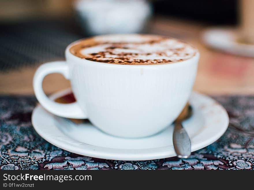 A cup of coffee with milk foam and cinnamon or cacao powder on top.