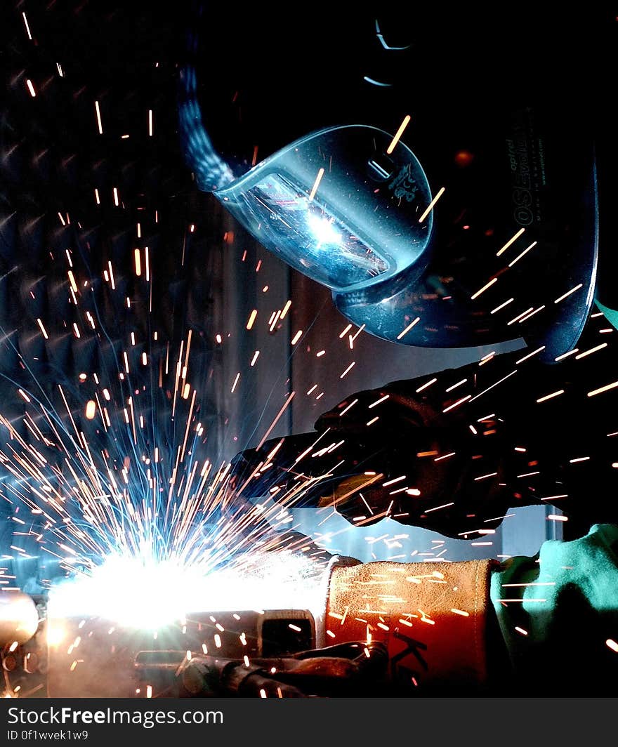 Person in Welding Mask While Welding a Metal Bar