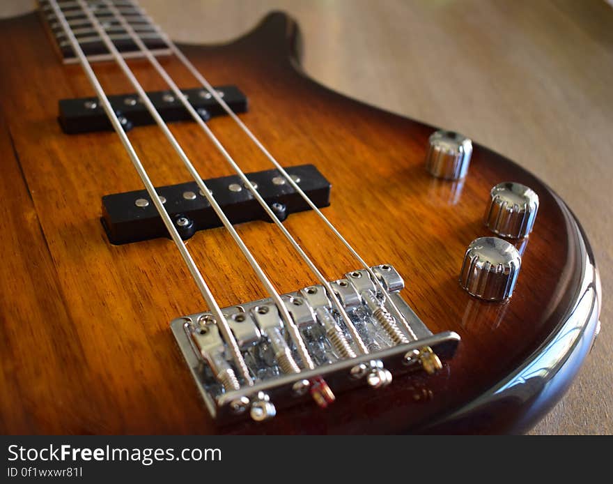 Close up of a glossy wood guitar with chrome dials.