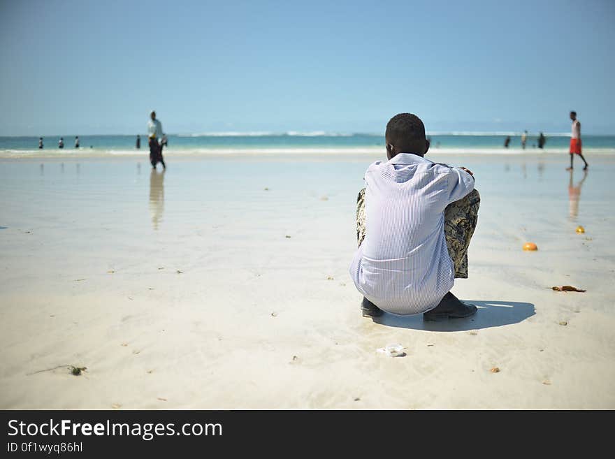 A boy sits on Lido beach in Mogadishu, Somalia, as people swim in the water and walk along the beach on April 15. Despite the continued threat of al Shabaab in Somalia, much of daily life in Mogadishu has returned to normal. AU UN IST / TOBIN JONES. A boy sits on Lido beach in Mogadishu, Somalia, as people swim in the water and walk along the beach on April 15. Despite the continued threat of al Shabaab in Somalia, much of daily life in Mogadishu has returned to normal. AU UN IST / TOBIN JONES.