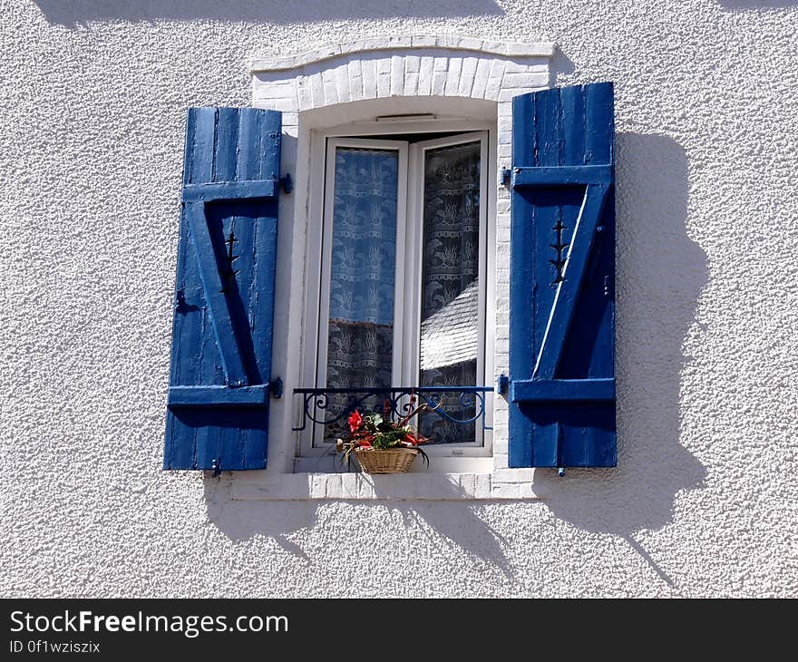 A wall and a window with blue shutters.