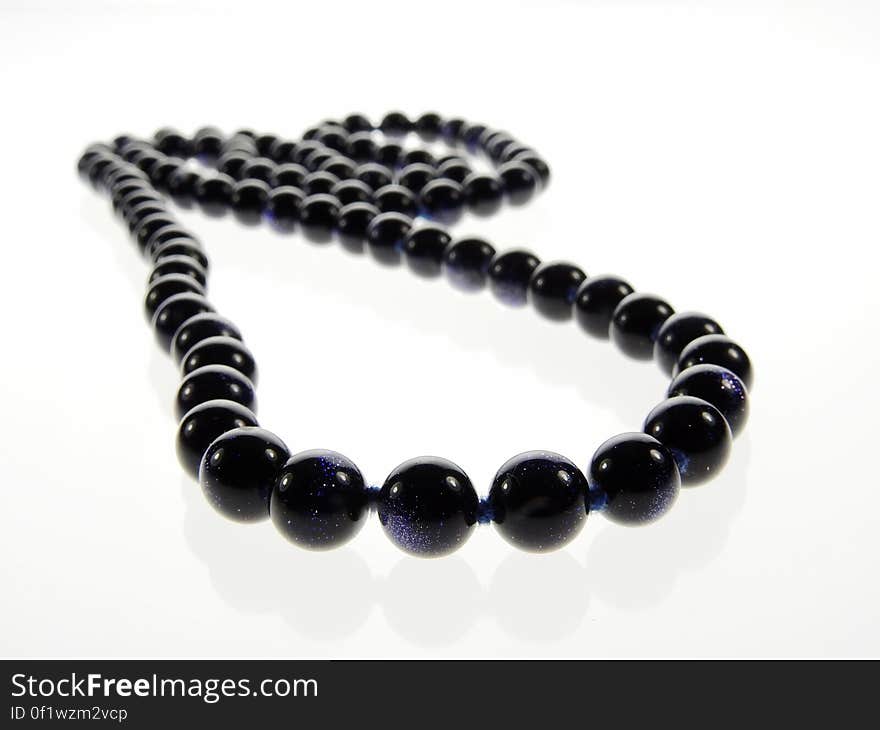 A black pearl necklace on white background. A black pearl necklace on white background.