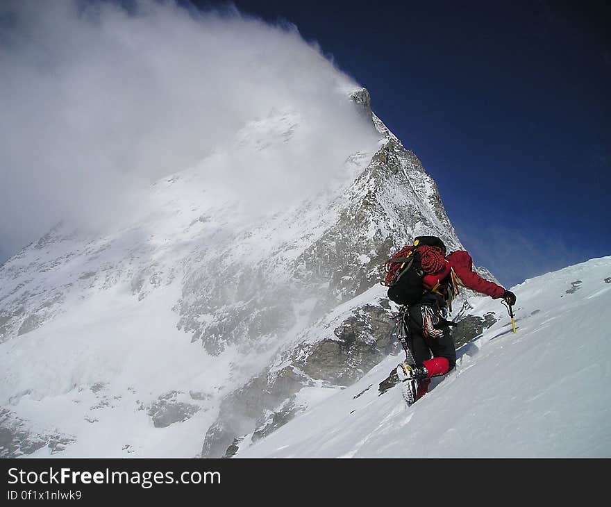 A mountain climber on a steep snowy hill with snow.