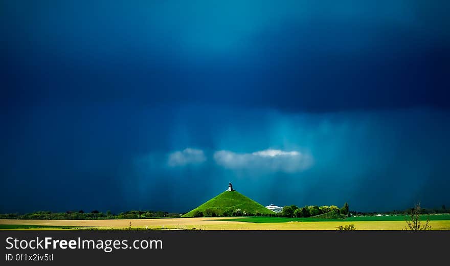 A monument on a green hill with dark stormy skies. A monument on a green hill with dark stormy skies.