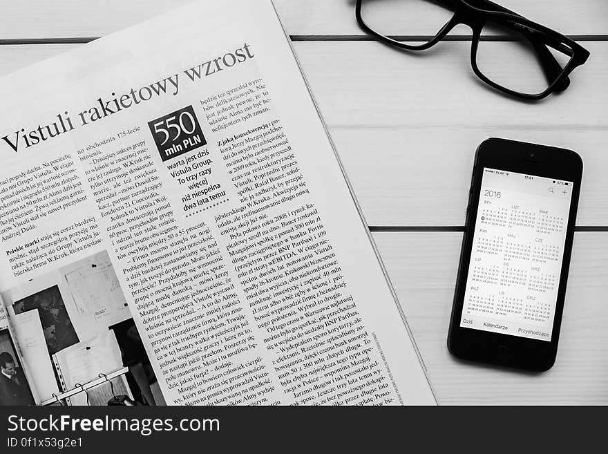 A newspaper on table with a mobile phone with calendar app. A newspaper on table with a mobile phone with calendar app.