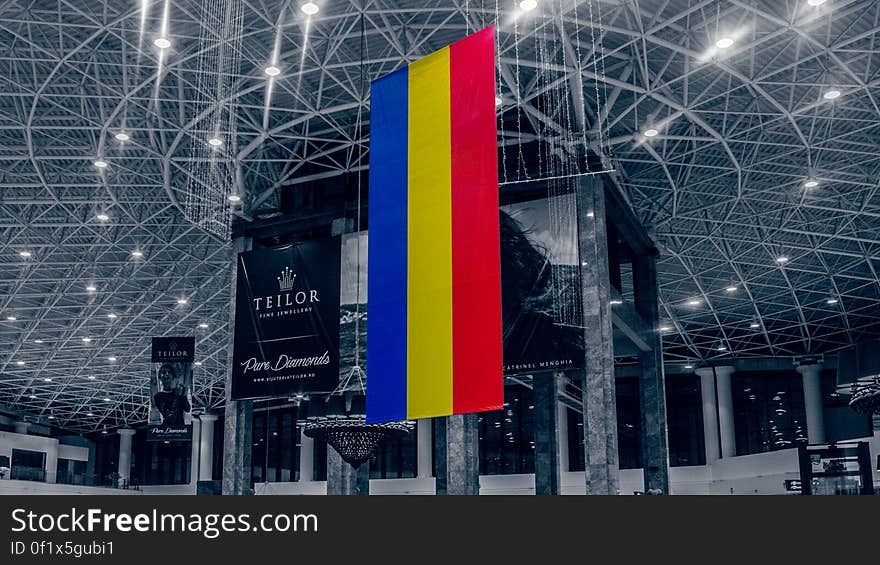 The Romanian flag hanging from a ceiling in a conference center or mall.