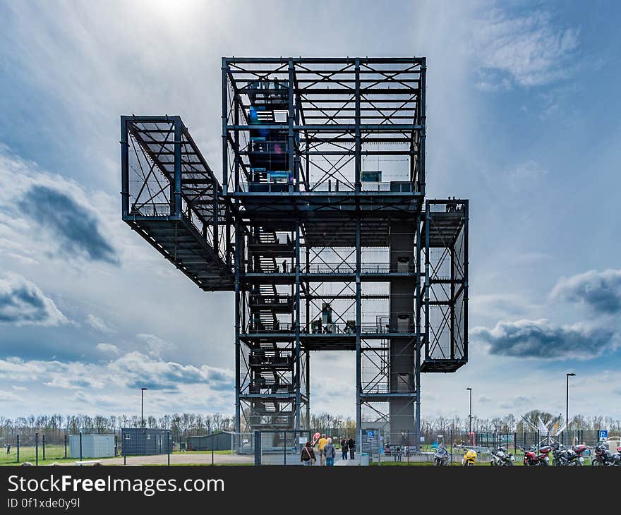 Exterior of tall steel mining tower with dramatic cloudscape background.