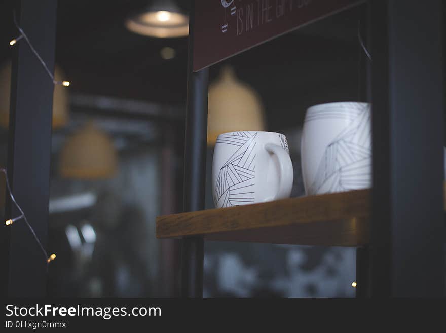 A coffee shop with close up on a shelf with coffee cups.