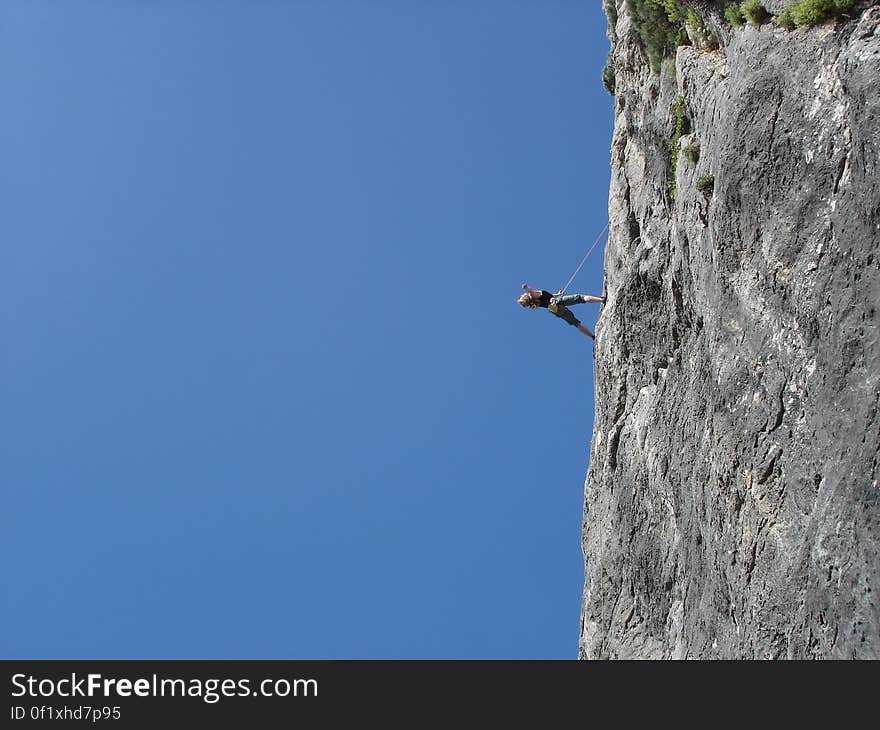 Man Standing on Rock Against Clear Blue Sky