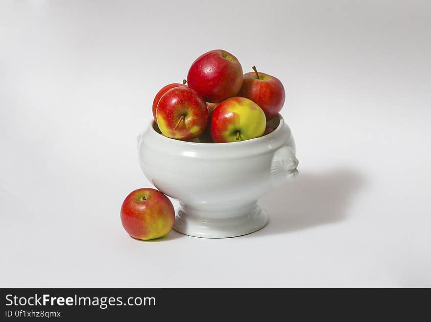 Ceramic bowl of fresh red and green apples, white studio background. Ceramic bowl of fresh red and green apples, white studio background.