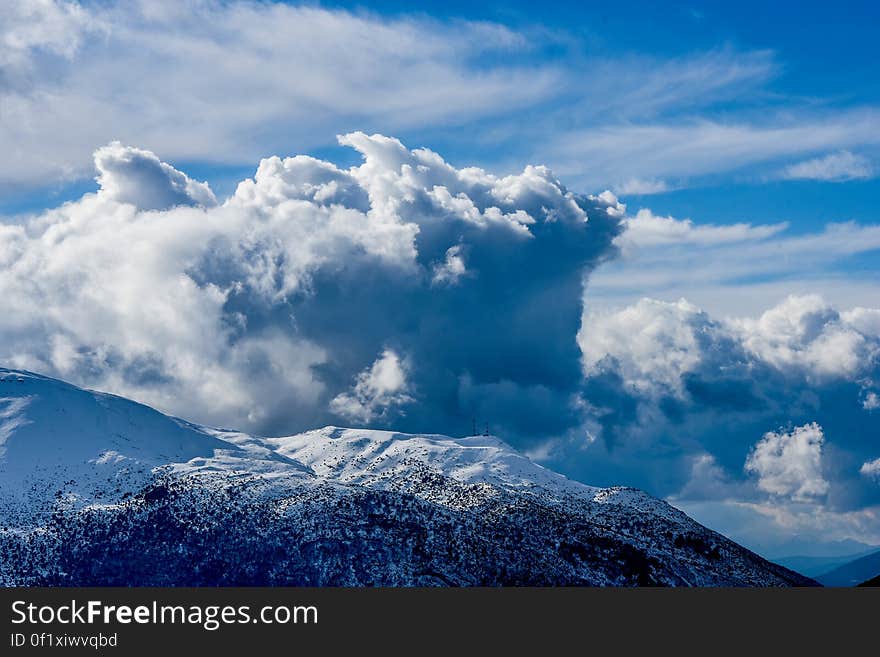 A big cloud formation over the peaks of snowy mountains. A big cloud formation over the peaks of snowy mountains.