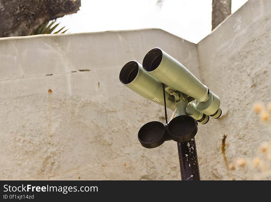 Binoculars on a stand in front of a wall. Binoculars on a stand in front of a wall.