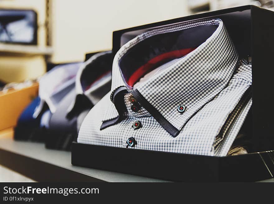 Closeup of check designer shirts in boxes showing buttoned down collars, two color lining at neck and with selective focus on nearest shirt. Closeup of check designer shirts in boxes showing buttoned down collars, two color lining at neck and with selective focus on nearest shirt.