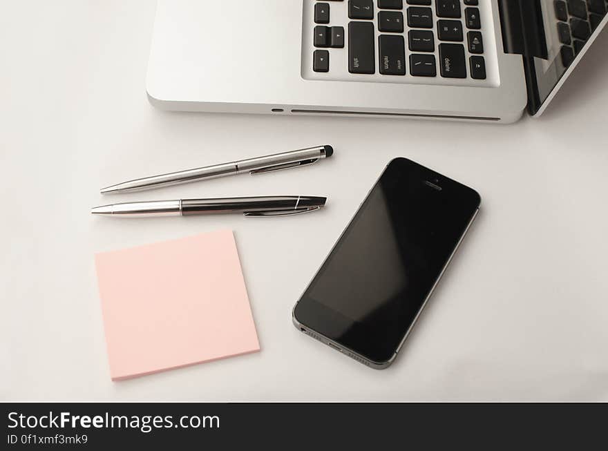 Laptop, smartphone, pens and a blank note sticker on a table. Laptop, smartphone, pens and a blank note sticker on a table.