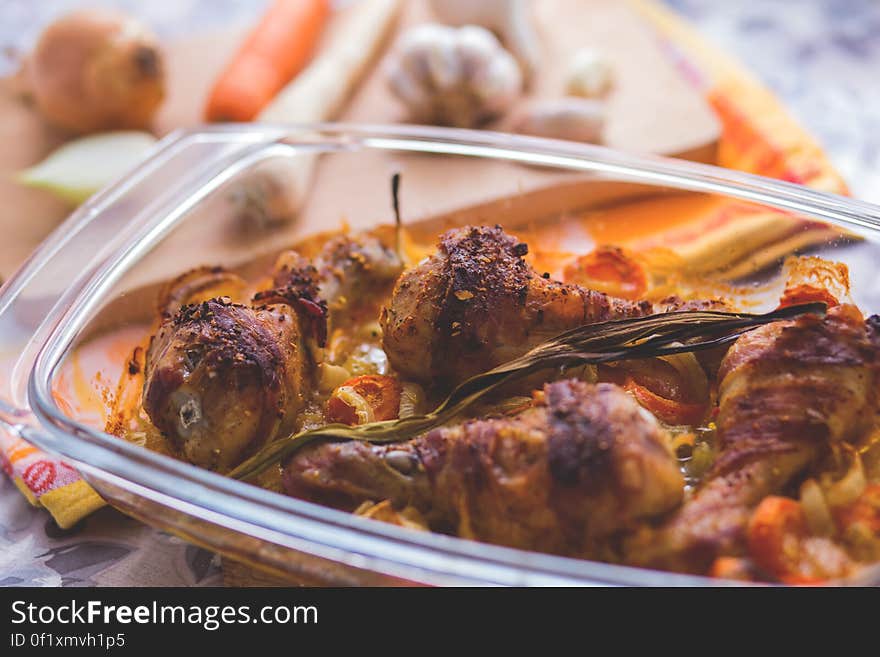 Roast chicken drumsticks with vegetables in a refractory bowl.