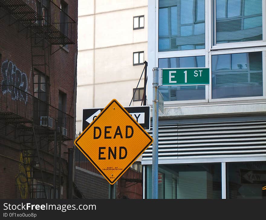 A yellow dead end street sign and buildings in the background. A yellow dead end street sign and buildings in the background.